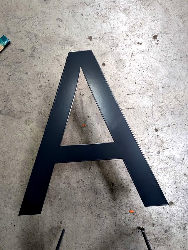 Aluminiowa litera 3D „A” po malowaniu proszkowym w kolorze czarnym, gotowa do montażu.