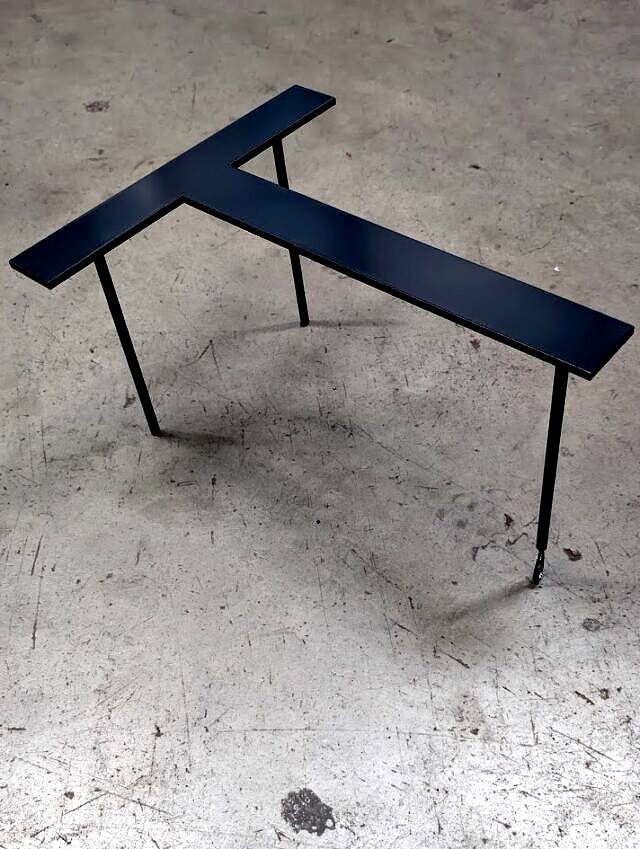 Aluminiowa litera 3D w kolorze czarnym po malowaniu proszkowym, ustawiona na stojaku.