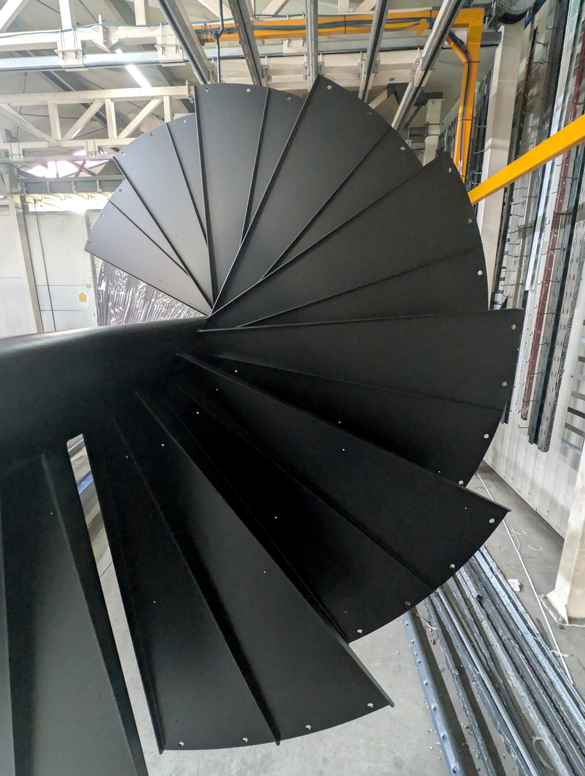 Schody spiralne stalowe po malowaniu proszkowym w kolorze RAL 9005 – jednolita czarna powłoka na elemencie do 8 m.