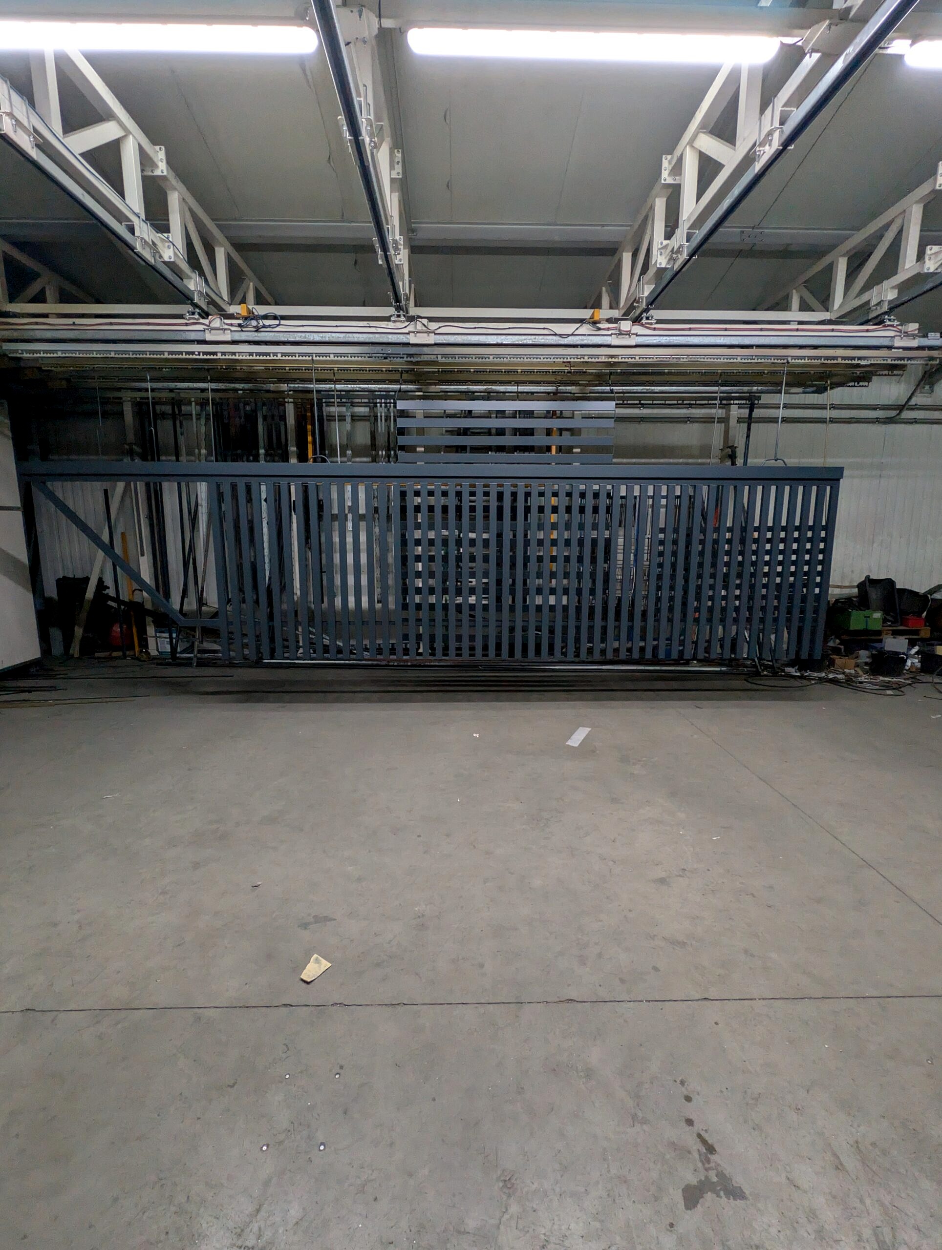 Duża brama aluminiowa po malowaniu proszkowym RAL 7016 mat, zawieszona na linii lakierniczej w Lakierni Koczargi.