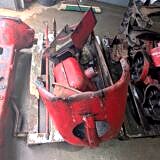 Uszkodzona maska traktora oraz metalowe elementy przygotowane do renowacji i malowania proszkowego