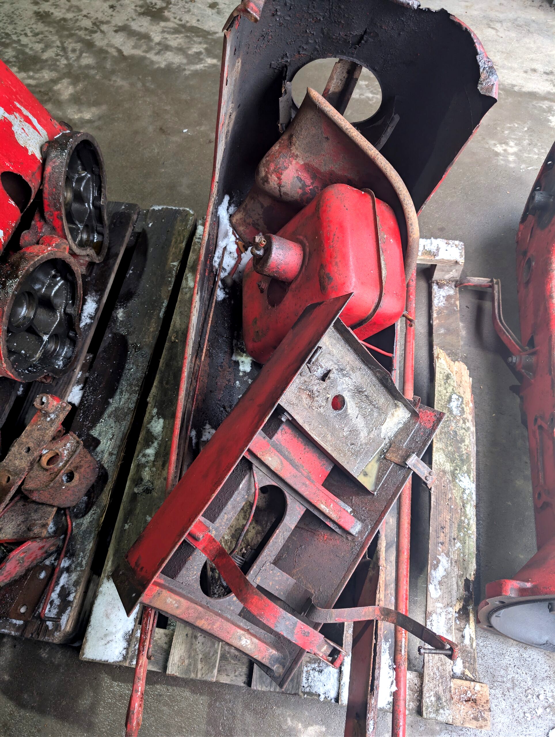 Metalowe elementy maski traktora w trakcie przygotowania do renowacji i lakierowania